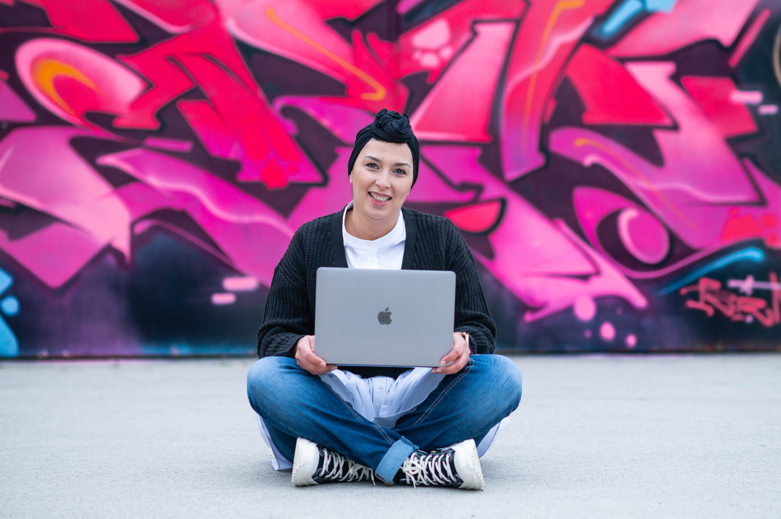 Unternehmering mit Notebook vor eine Grafiti Wand